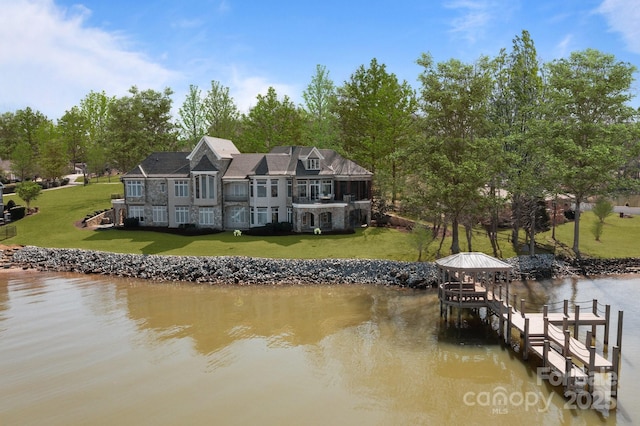 dock area with a water view, a lawn, boat lift, and a balcony