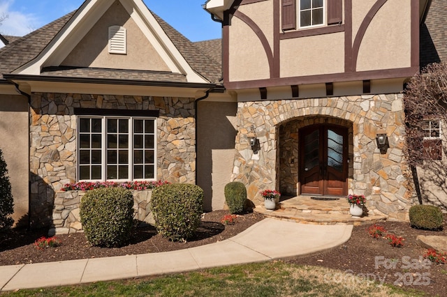 property entrance featuring stone siding, roof with shingles, and stucco siding