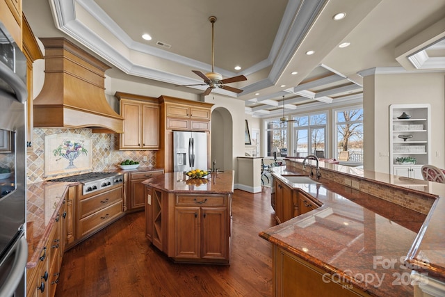 kitchen featuring a large island, stainless steel appliances, dark wood-type flooring, a sink, and dark stone counters