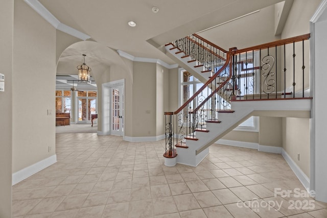 tiled foyer entrance with stairway, baseboards, arched walkways, and ornamental molding