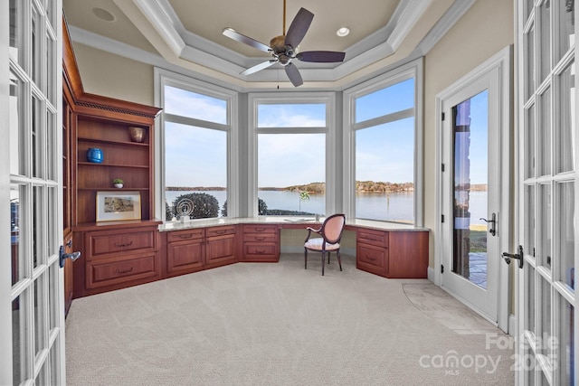 office area featuring ornamental molding, a water view, a tray ceiling, french doors, and built in desk