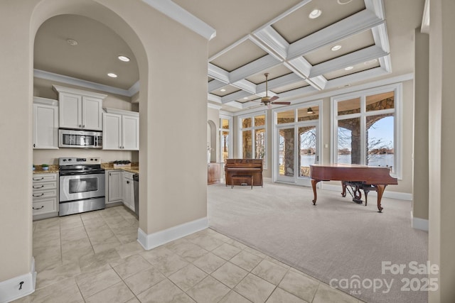 interior space featuring arched walkways, light colored carpet, coffered ceiling, appliances with stainless steel finishes, and ornamental molding