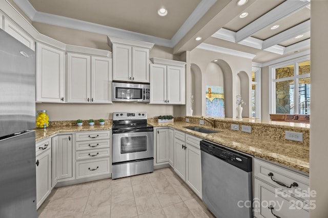 kitchen with light stone counters, stainless steel appliances, ornamental molding, white cabinets, and a sink