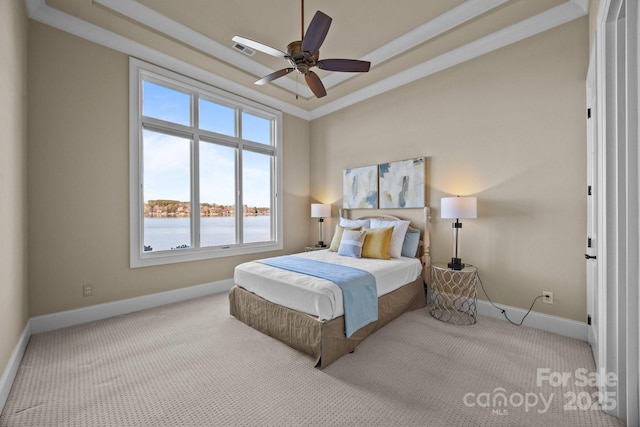 carpeted bedroom with a tray ceiling, a water view, visible vents, and baseboards