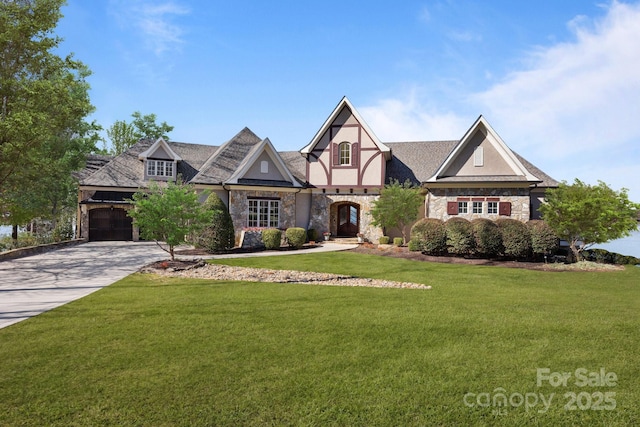 tudor-style house featuring a front yard, concrete driveway, an attached garage, stone siding, and stucco siding