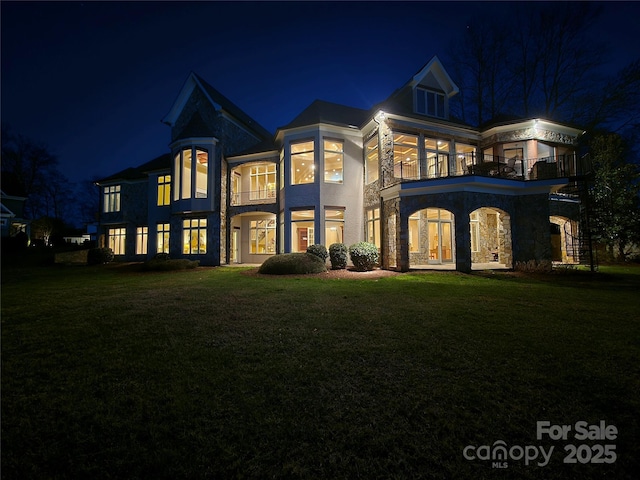 134 Larkhaven Ln, Mooresville, NC 28117 - back of house at night with a balcony, a yard, and stone siding