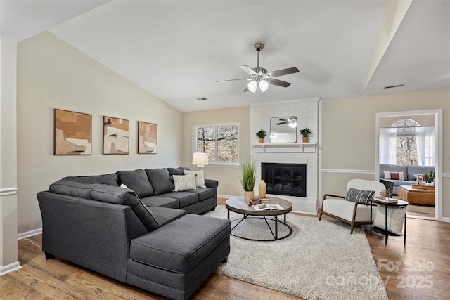 living area featuring vaulted ceiling, a fireplace, plenty of natural light, and wood finished floors