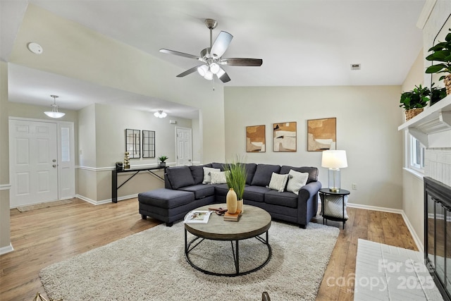 living room with lofted ceiling, a fireplace, baseboards, and wood finished floors