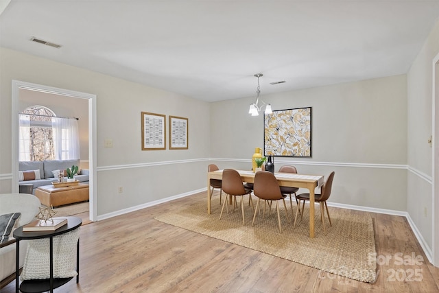 dining room with a notable chandelier, light wood-type flooring, visible vents, and baseboards