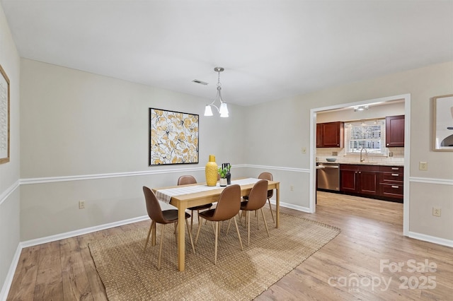 dining area with light wood finished floors, visible vents, and baseboards