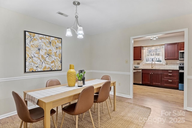 dining area featuring visible vents, a notable chandelier, light wood-style flooring, and baseboards