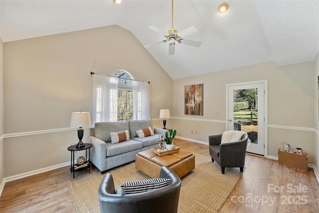 living room with baseboards, plenty of natural light, high vaulted ceiling, and wood finished floors