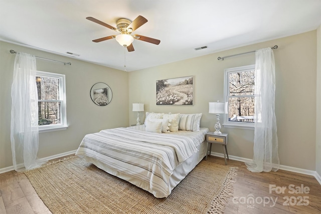 bedroom featuring visible vents, baseboards, and wood finished floors