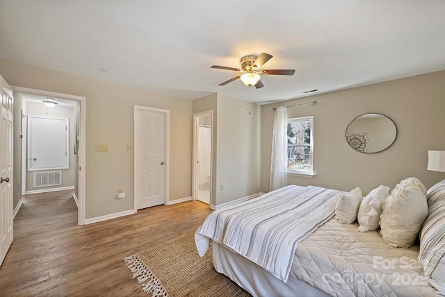 bedroom featuring a ceiling fan, wood finished floors, visible vents, and baseboards