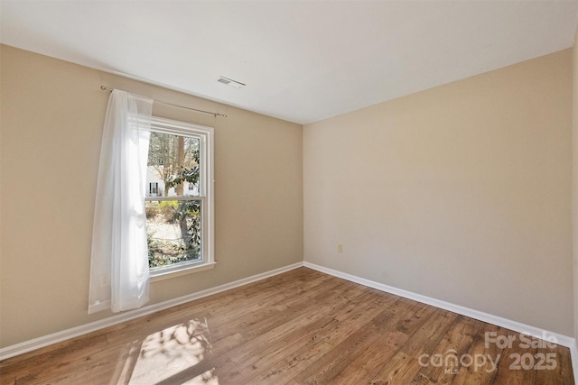 spare room featuring baseboards, visible vents, and light wood-style floors