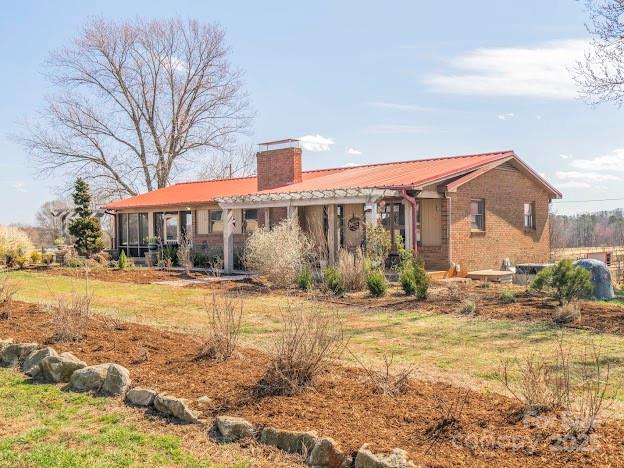 rear view of house featuring brick siding and a chimney