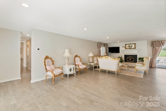 living room with light wood-style floors, a fireplace, baseboards, and recessed lighting