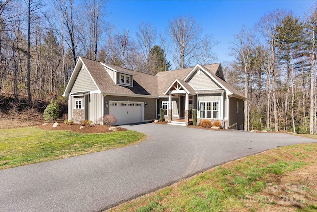 craftsman house featuring aphalt driveway, an attached garage, roof with shingles, a front lawn, and board and batten siding