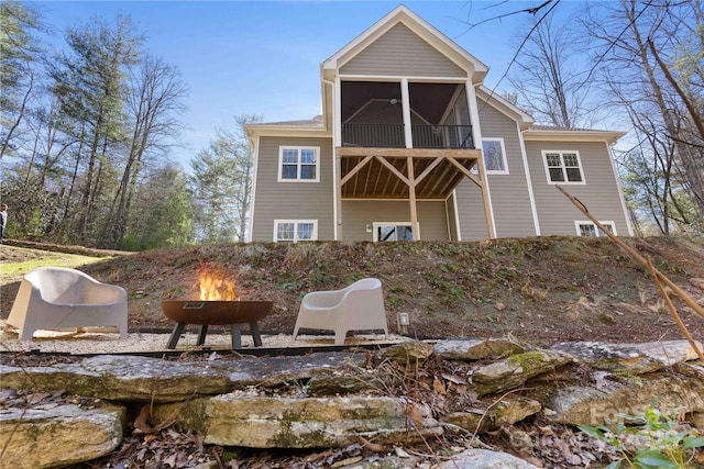 back of property featuring an outdoor fire pit and a sunroom