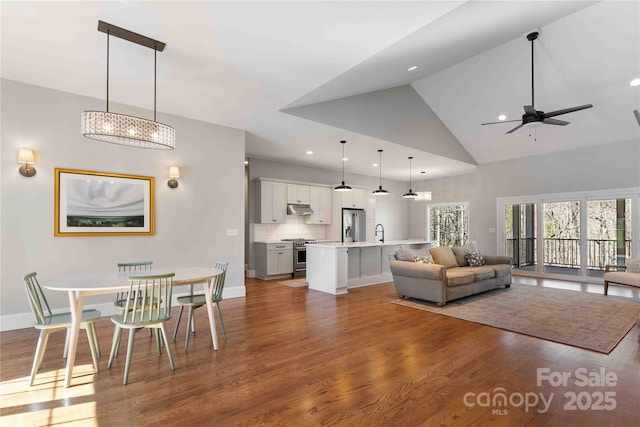 living area featuring high vaulted ceiling, recessed lighting, wood finished floors, a ceiling fan, and baseboards