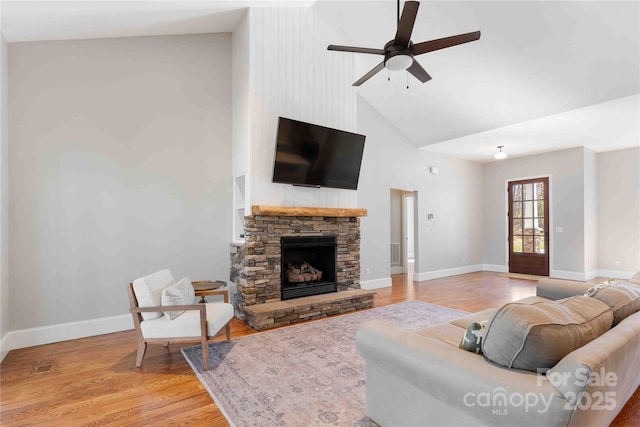 living room featuring high vaulted ceiling, a fireplace, light wood-style flooring, and baseboards