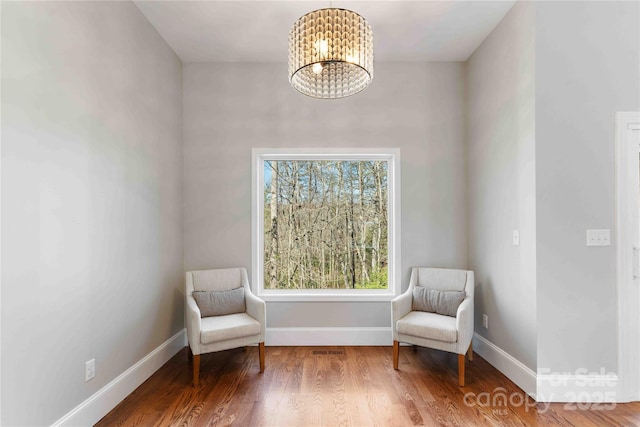 sitting room with a chandelier, wood finished floors, and baseboards