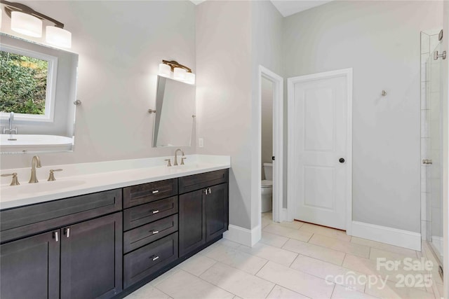 full bath featuring baseboards, a sink, toilet, and double vanity