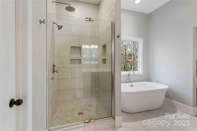 bathroom featuring a freestanding tub, a shower stall, baseboards, and tile patterned floors