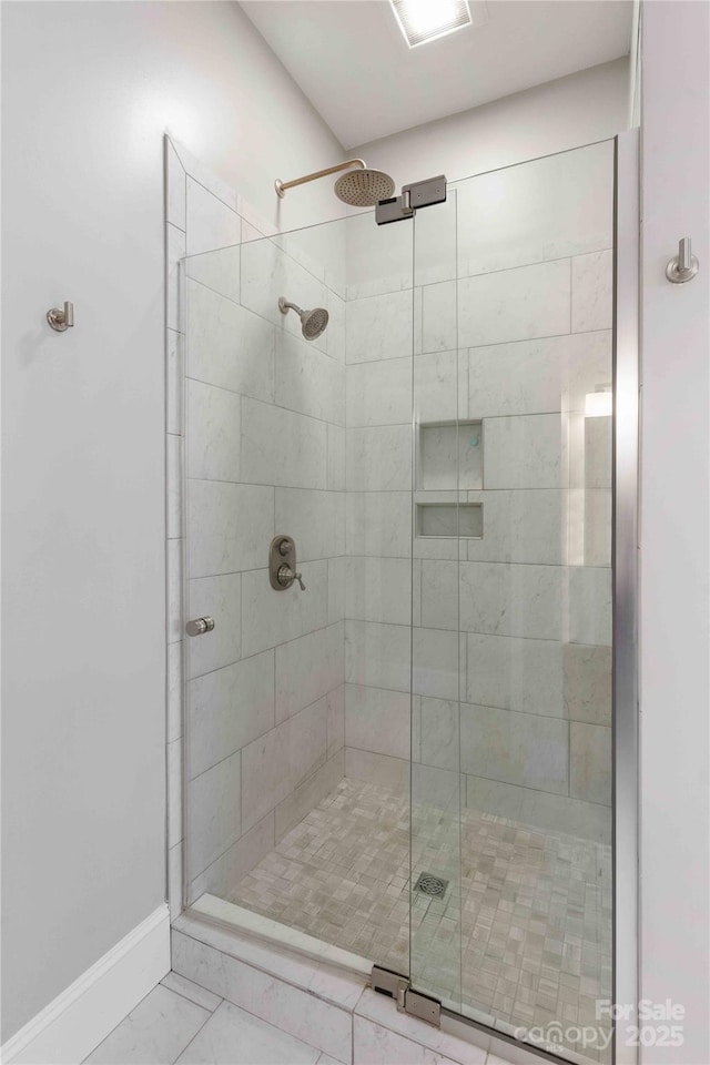 full bath featuring a stall shower and baseboards