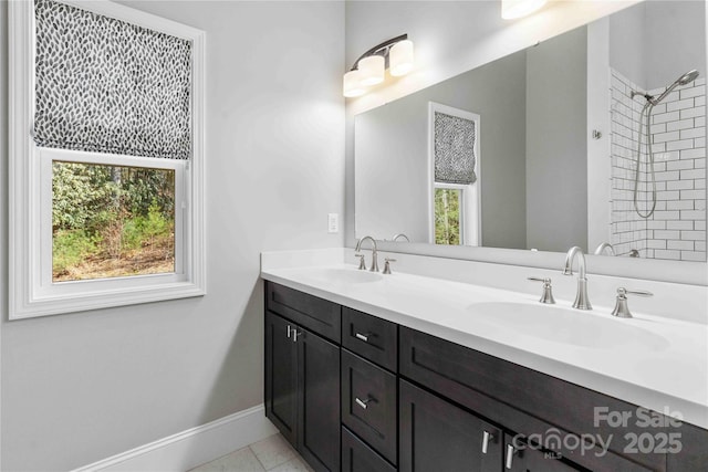 full bath featuring double vanity, tile patterned floors, a sink, and baseboards