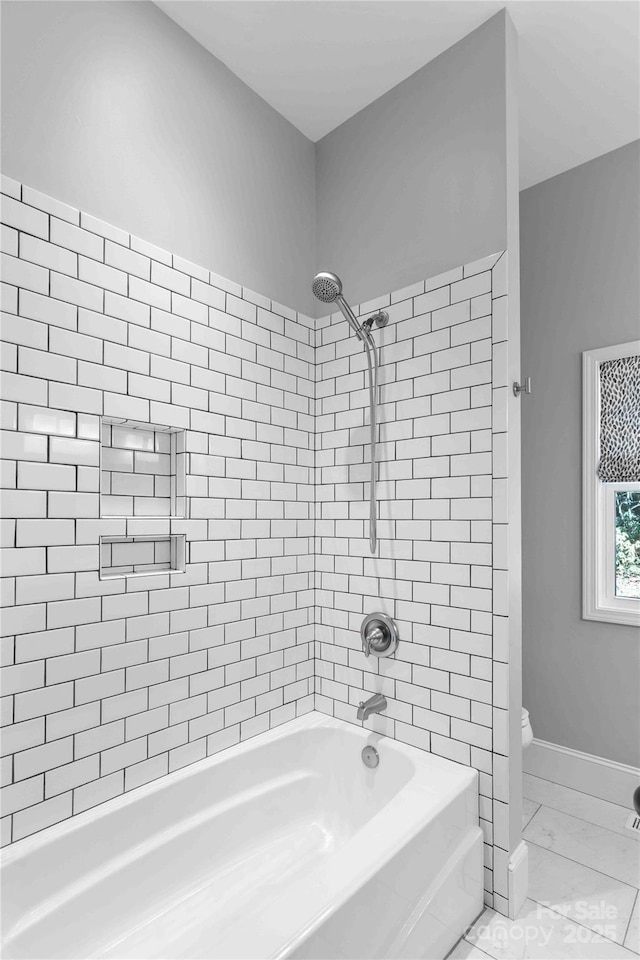 bathroom featuring toilet, marble finish floor, bathtub / shower combination, and baseboards