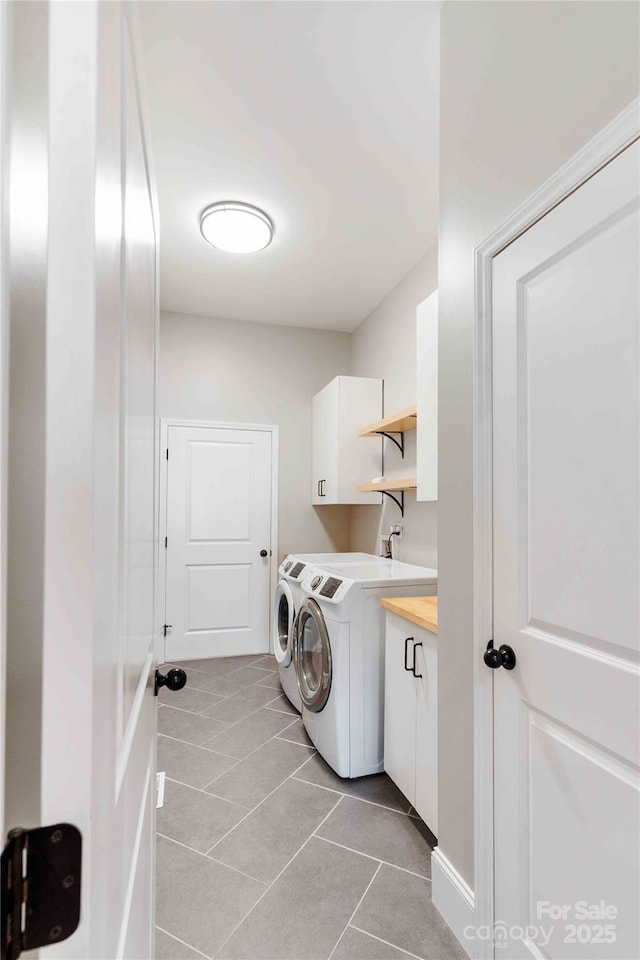 clothes washing area with washing machine and dryer, cabinet space, and light tile patterned floors