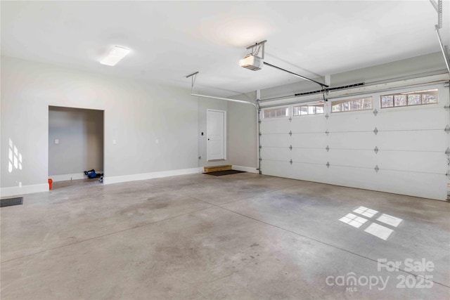 garage with a garage door opener, visible vents, and baseboards