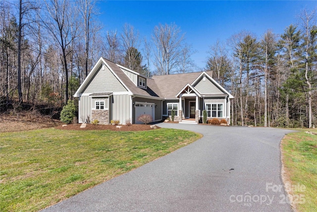 view of front of house featuring a garage, stone siding, aphalt driveway, a front lawn, and board and batten siding