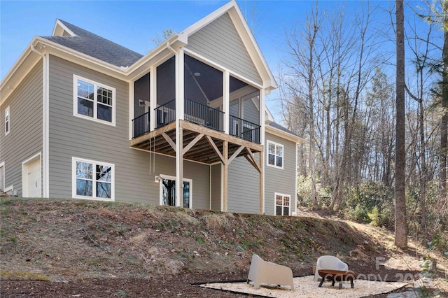 rear view of house with a shingled roof and a sunroom