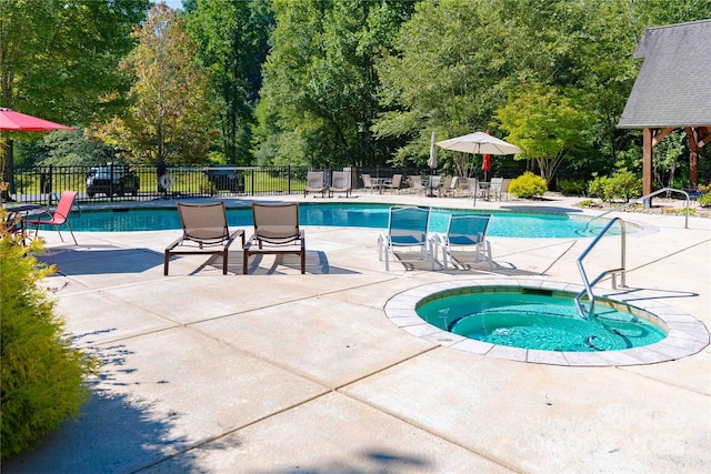 pool with a community hot tub, a patio area, and fence