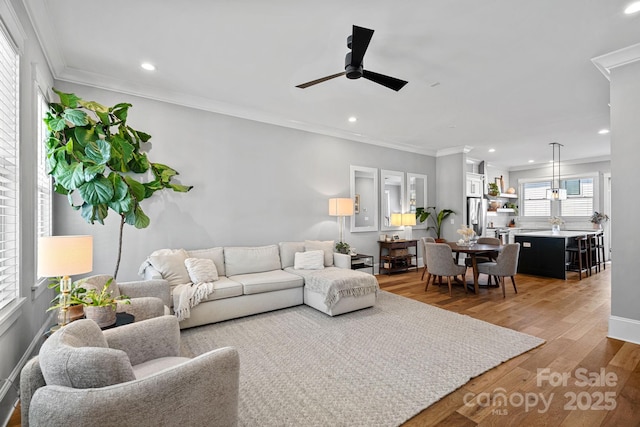 living area with recessed lighting, light wood-type flooring, and ornamental molding