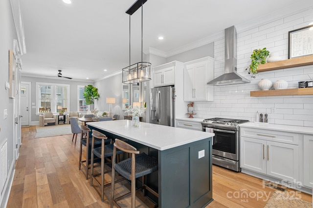 kitchen featuring appliances with stainless steel finishes, a breakfast bar area, wall chimney exhaust hood, crown molding, and decorative backsplash