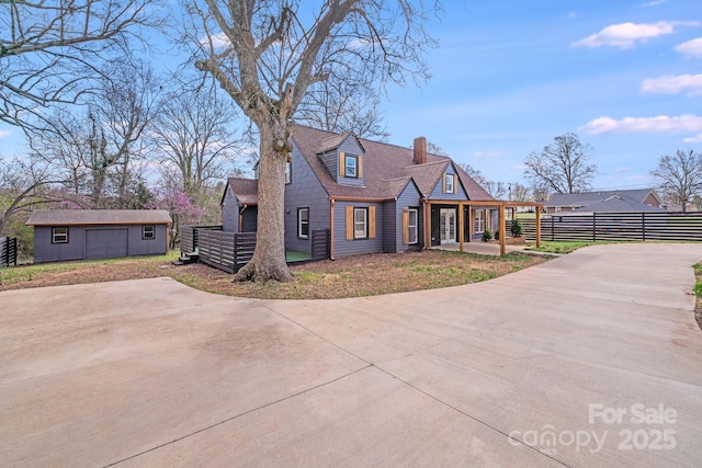 new england style home featuring an outbuilding, fence, and a chimney