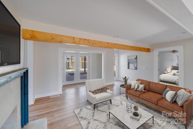 living area with french doors, light wood-type flooring, and baseboards
