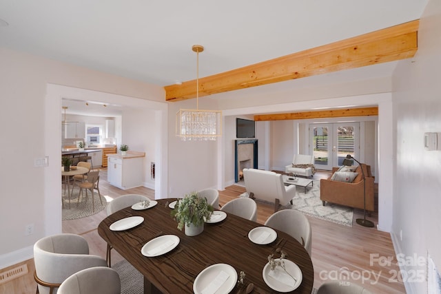 dining space featuring light wood finished floors, a chandelier, and baseboards
