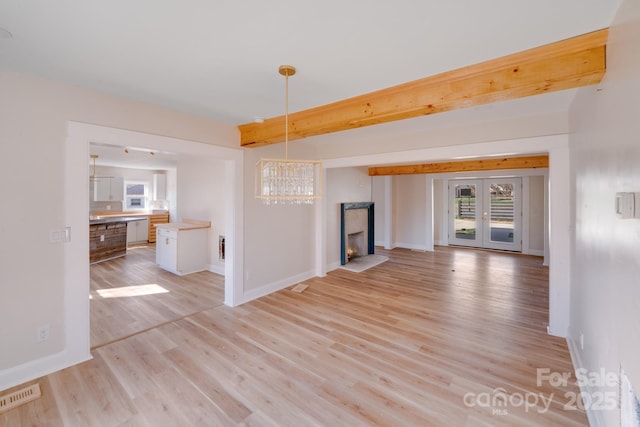 unfurnished living room featuring plenty of natural light, light wood finished floors, and baseboards