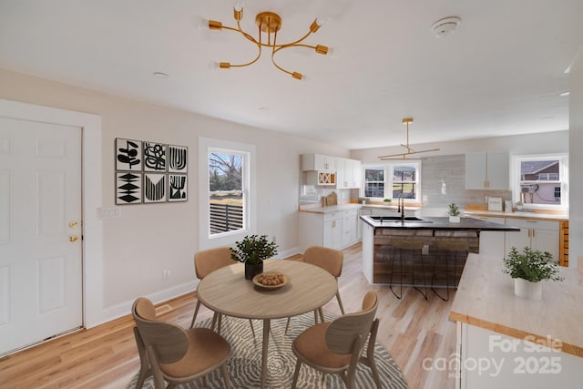 dining area with a chandelier, healthy amount of natural light, and light wood finished floors