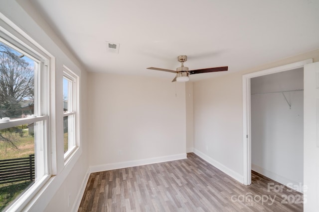 unfurnished bedroom featuring wood finished floors, baseboards, a closet, and ceiling fan