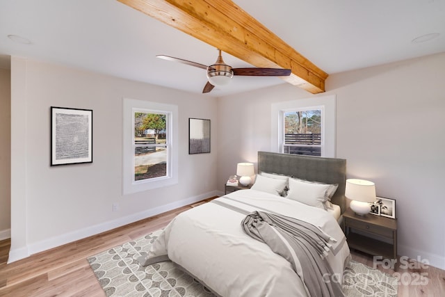 bedroom featuring multiple windows, baseboards, and beam ceiling