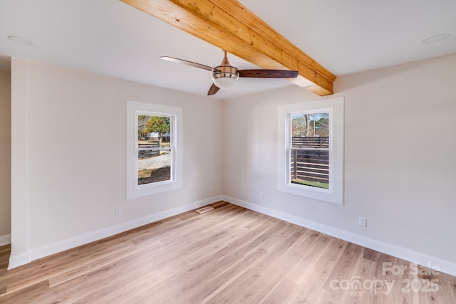 spare room featuring plenty of natural light, light wood-type flooring, baseboards, and beam ceiling