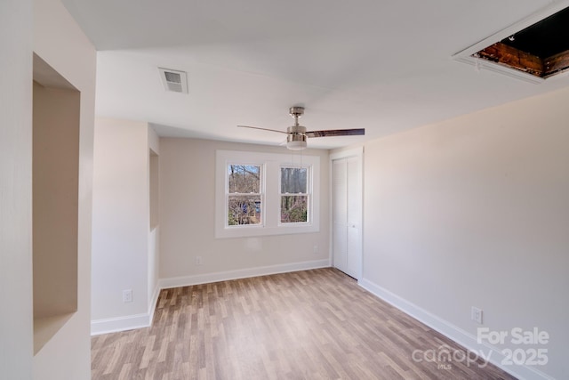 spare room featuring light wood-type flooring, a ceiling fan, and baseboards