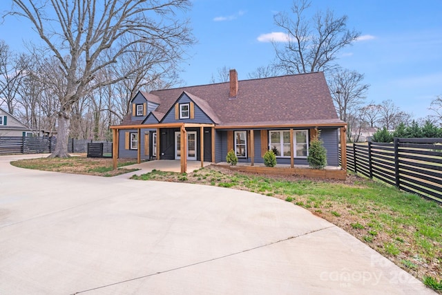 view of front of house featuring covered porch, a chimney, and fence
