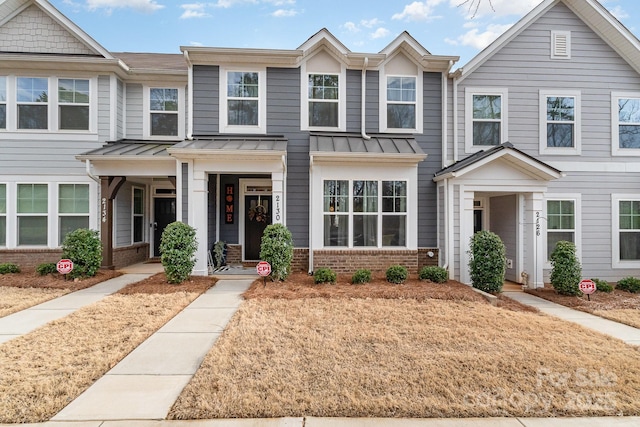 townhome / multi-family property featuring metal roof, brick siding, and a standing seam roof