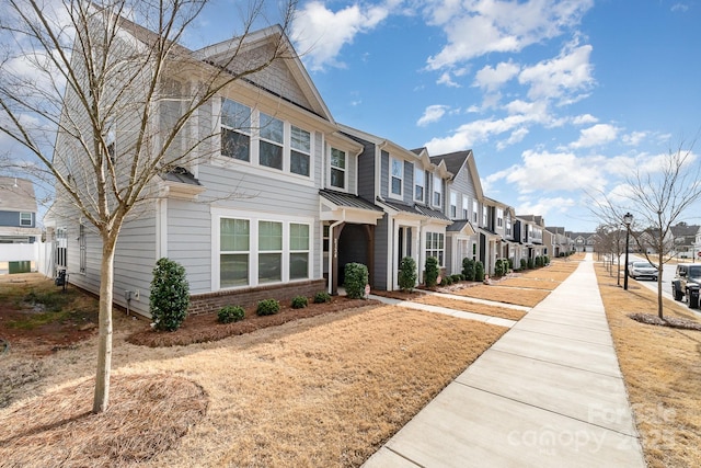 view of front of home featuring a residential view, a standing seam roof, brick siding, and metal roof